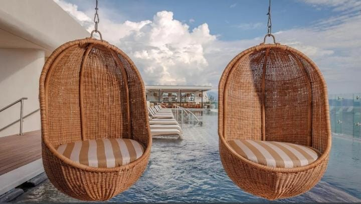 Asientos colgantes junto a una piscina con vista al mar