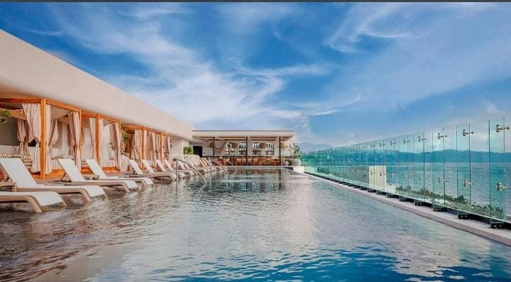 Piscina infinita y camastros con vista al mar